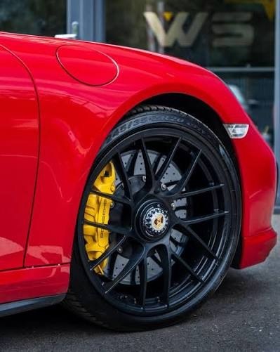 Powder coated black wheels with yellow calipers on a red 911
