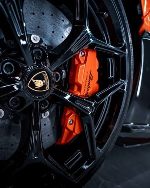 Lamborghini orange caliper behind gloss black wheel